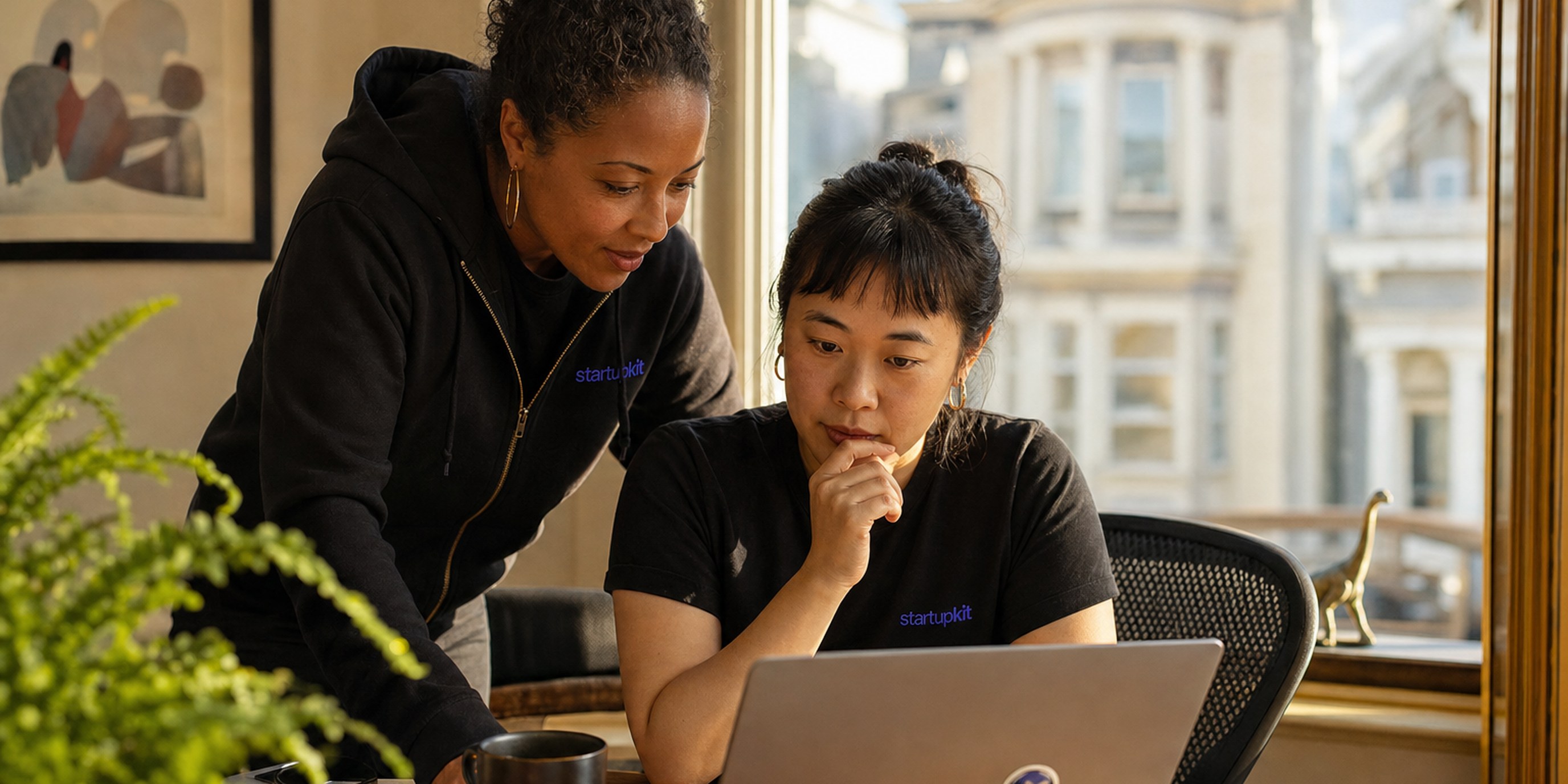 A startup founder at a sunlit home-office desk comparing a generic white-label ATS application form against her own branded careers page on a second monitor