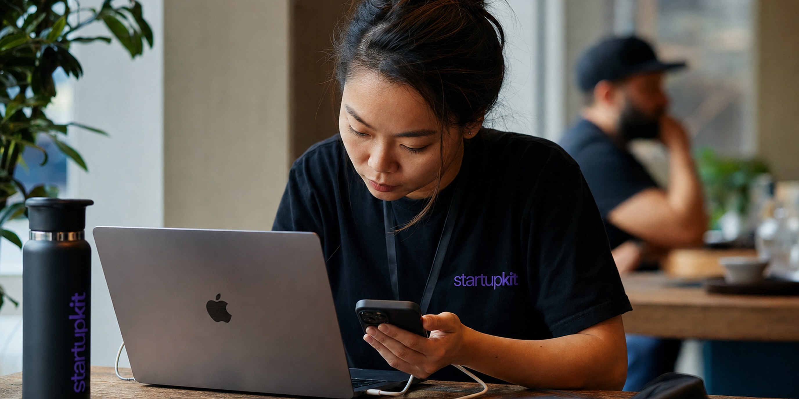 Mobile engineer profiling an iOS app on a physical iPhone wired to a MacBook running Xcode Instruments during a hiring portfolio review