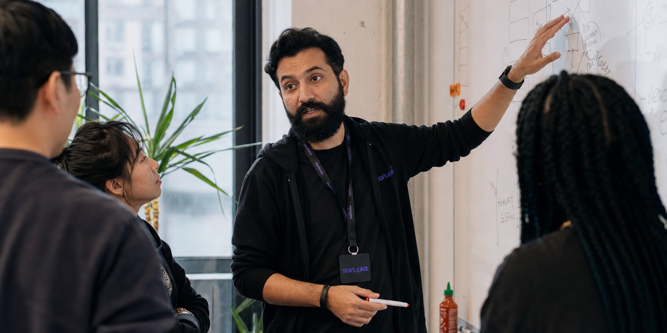 VP of Engineering leading a planning session at a whiteboard with an engineering team in a startup office